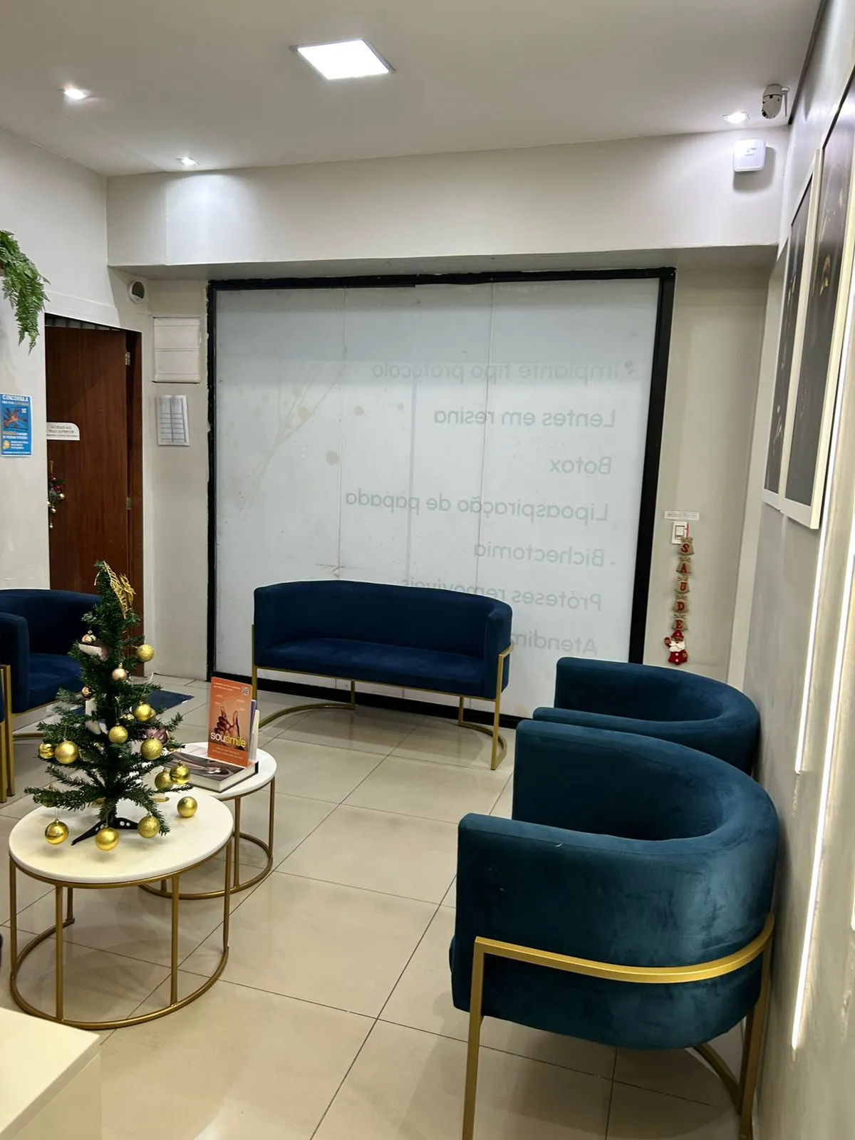 Sala de espera com sofás azuis e acesso aos consultórios