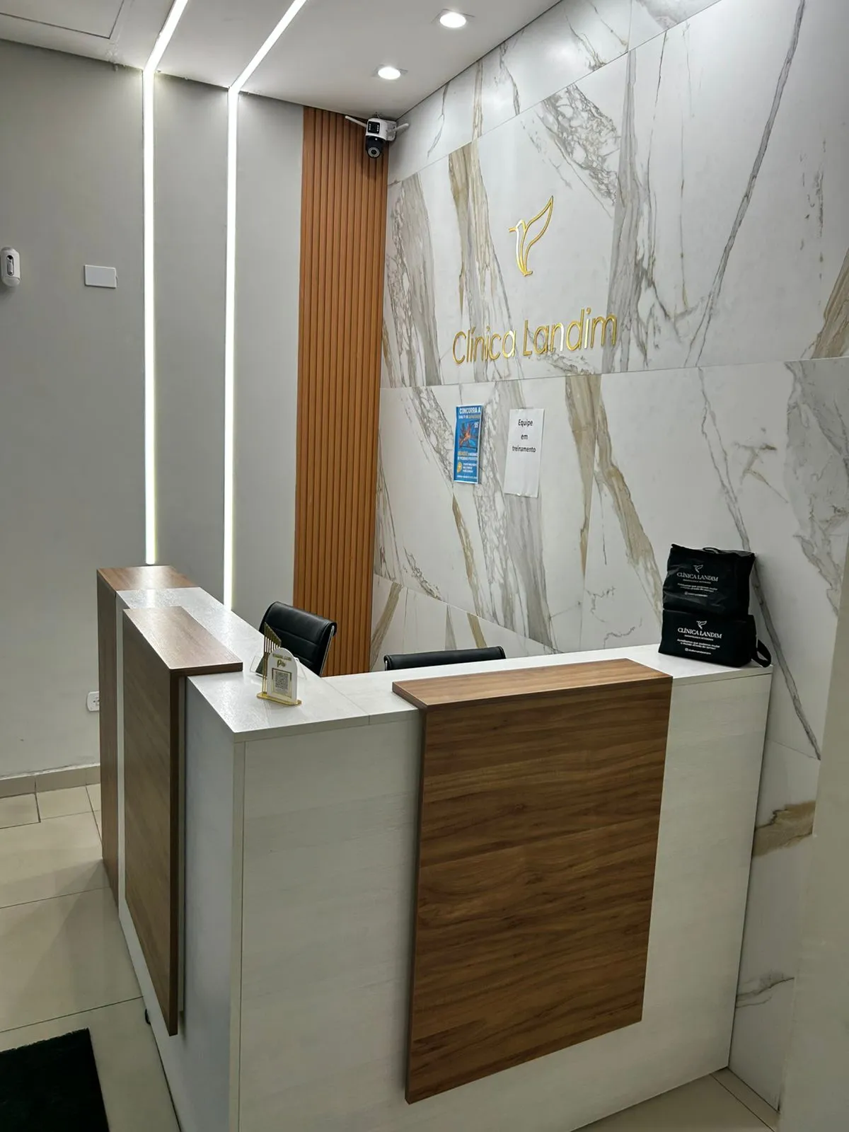 Recepção da Clínica Landim, com balcão de atendimento e parede de mármore